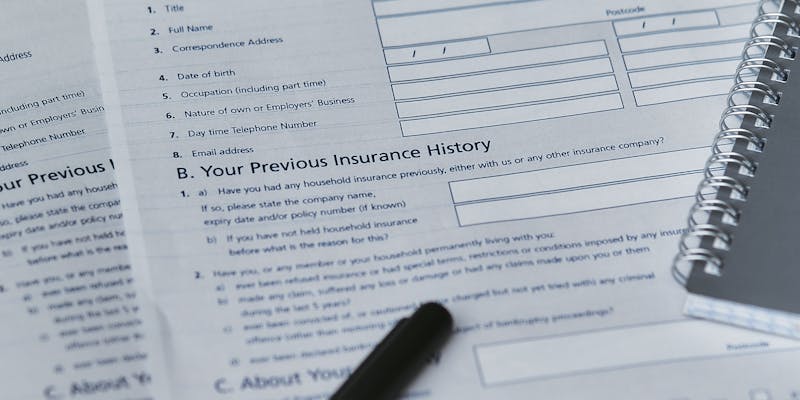 Homeowner reviewing insurance denial letter at kitchen table with damaged property documents