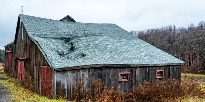 Damaged residential roof with missing shingles and exposed underlayment requiring insurance claim